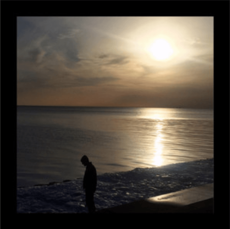 A silhouette of a person standing on a beach at sunset