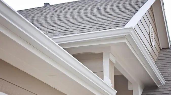 White gutters on a house with a gray sky background, suggesting a storm is approaching.
