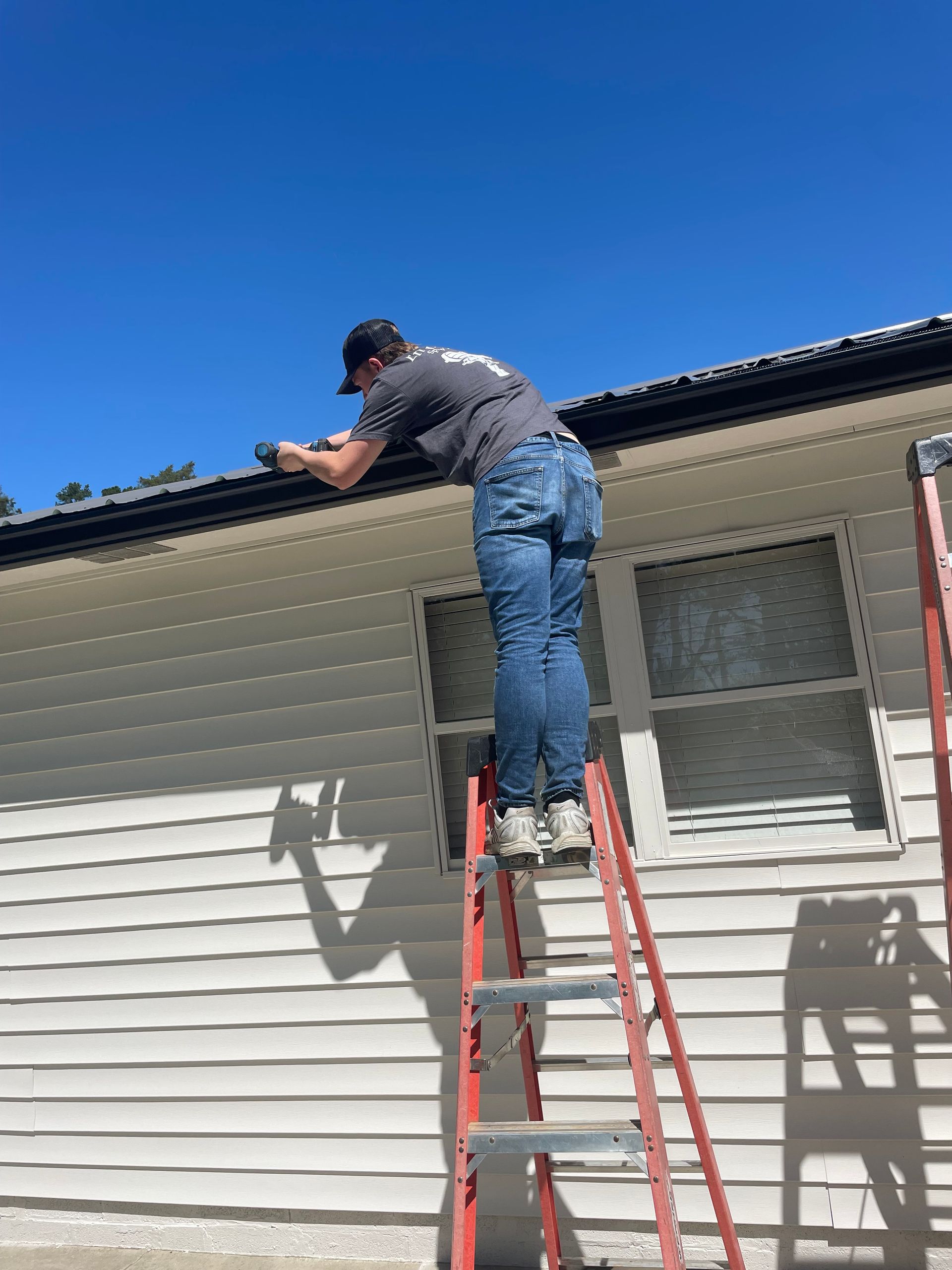 Wooden gable roof with dark brown trim and visible wood grain against a cloudy sky.