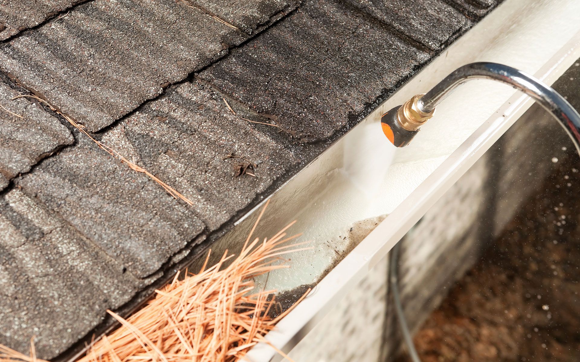 A person is cleaning a gutter with a hose.