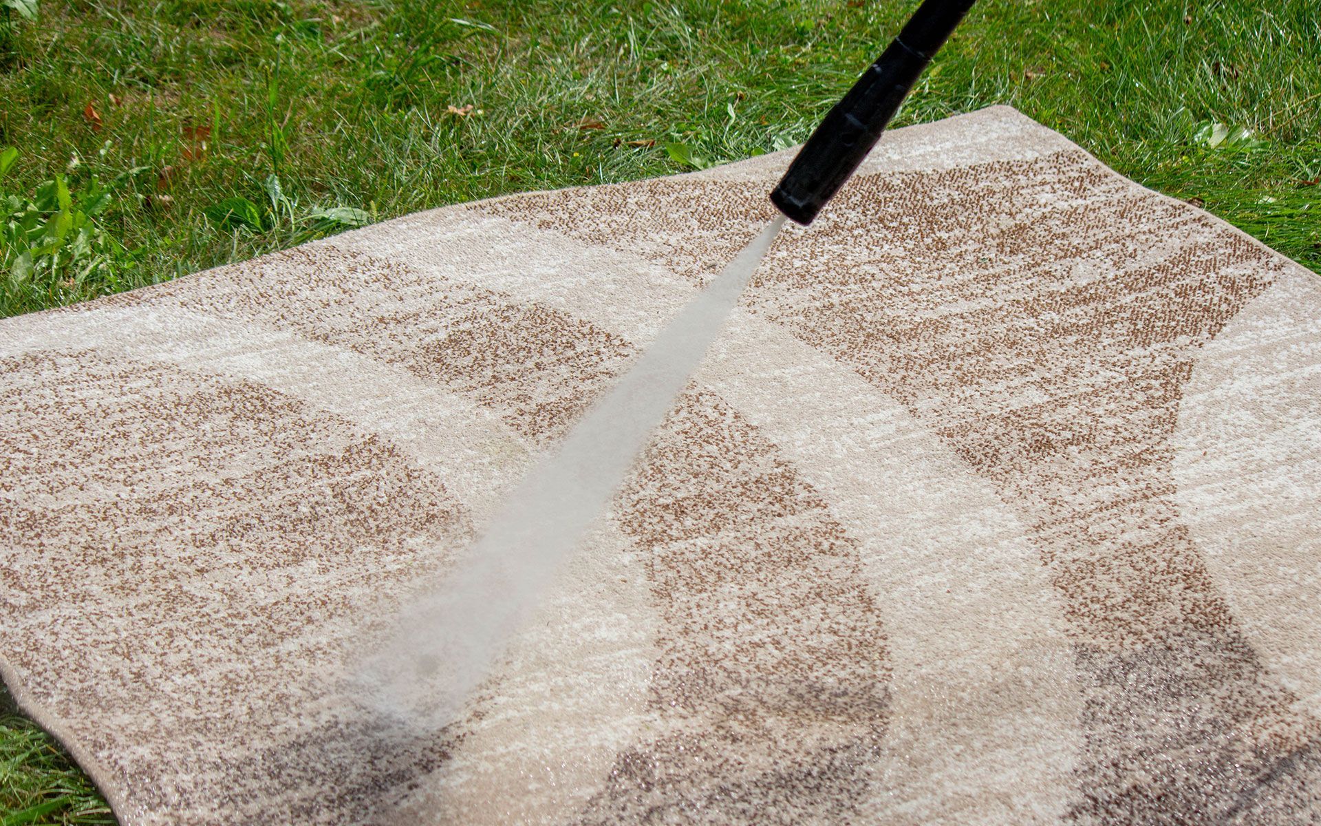 A person is cleaning a rug with a high pressure washer.