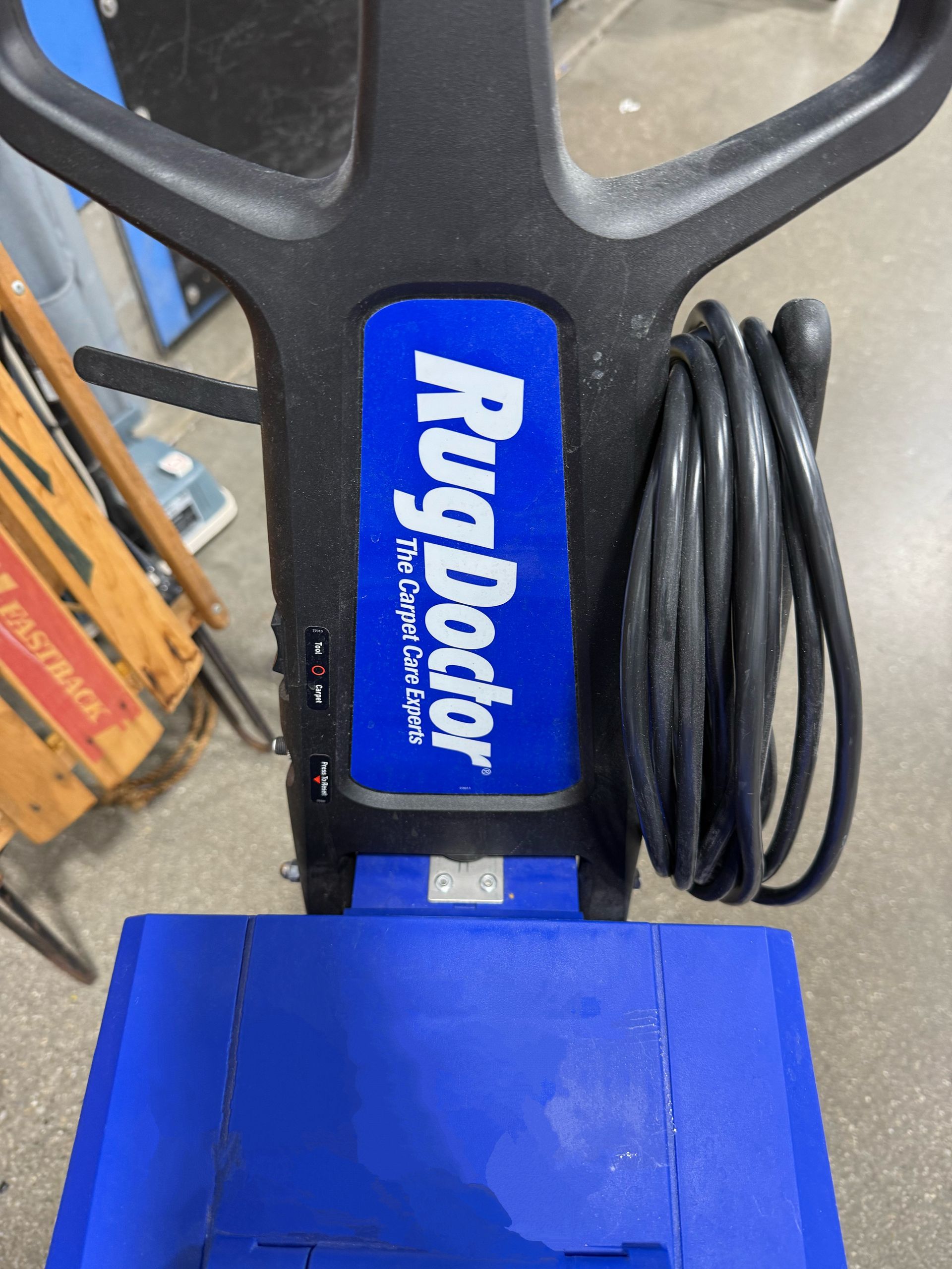A person is using a high pressure washer to clean a carpet.
