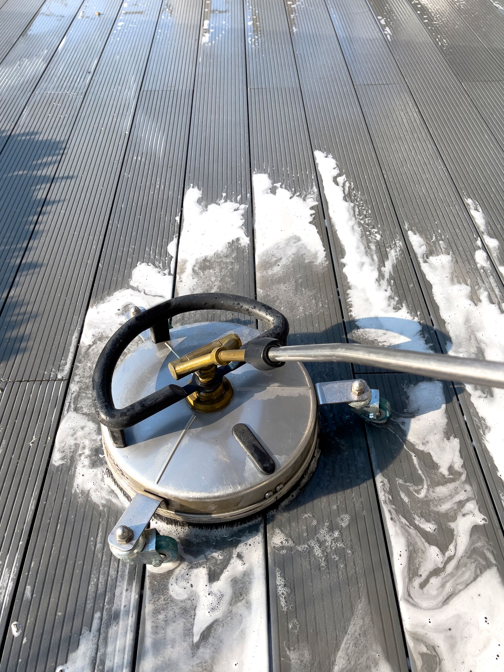A man is cleaning a brick wall with a high pressure washer.