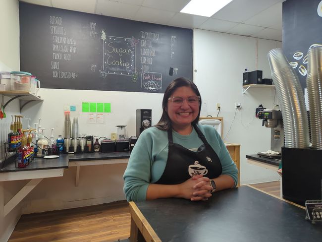 A woman in an apron is sitting at a counter in a restaurant.