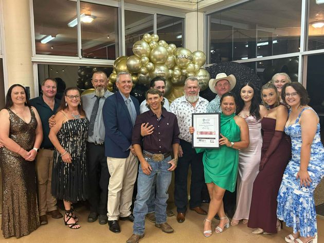 Group of people celebrating, holding award. Balloons in background. Indoors, formal attire — Campbell's Truck and Bobcat and Landscape Supplies In Gympie, QLD