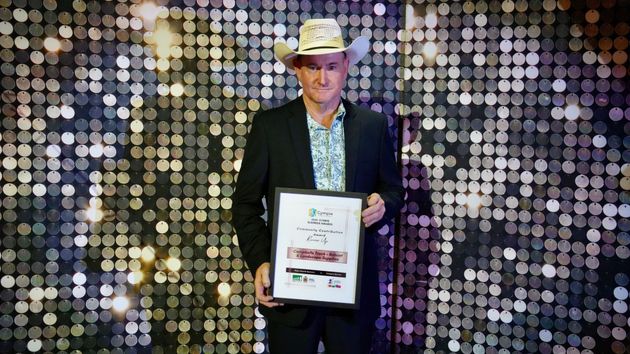 Man in cowboy hat holds award in front of sparkly backdrop — Campbell's Truck and Bobcat and Landscape Supplies In Gympie, QLD