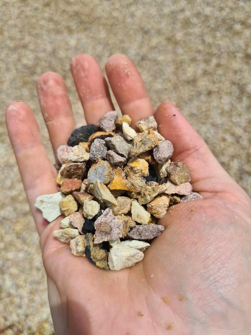 A Person Holding A Pile Of Small Honeycomb Rocks — Campbell's Truck and Bobcat and Landscape Supplies In Gympie, QLD