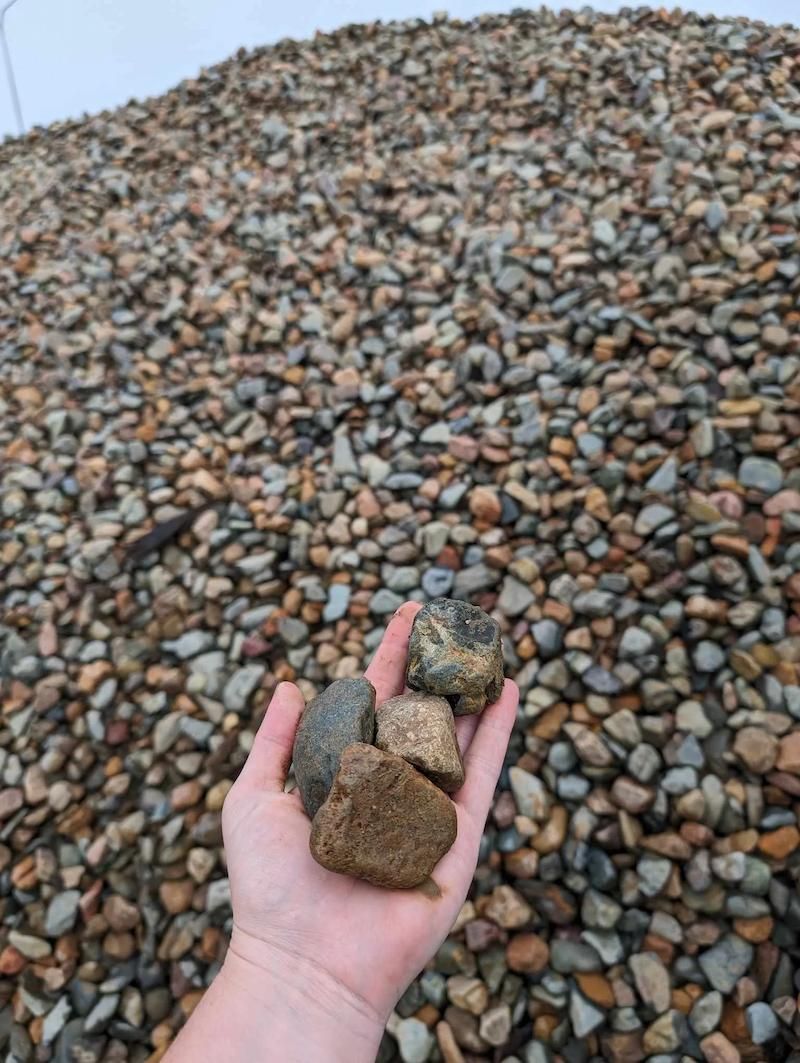 A Person Is Holding A Pile Of Rocks — Campbell's Truck and Bobcat and Landscape Supplies In Gympie, QLD