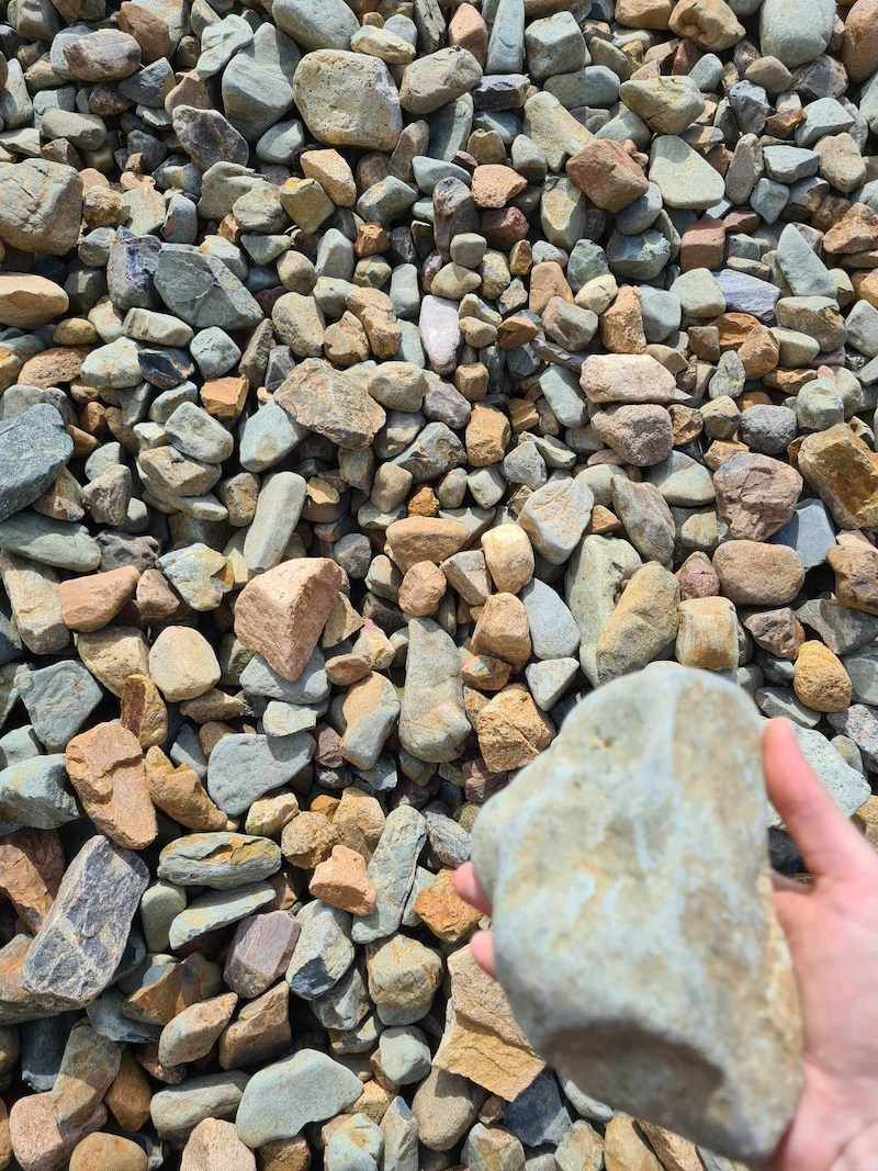 A Person Is Holding A Large Rock In Their Hand — Campbell's Truck and Bobcat and Landscape Supplies In Gympie, QLD