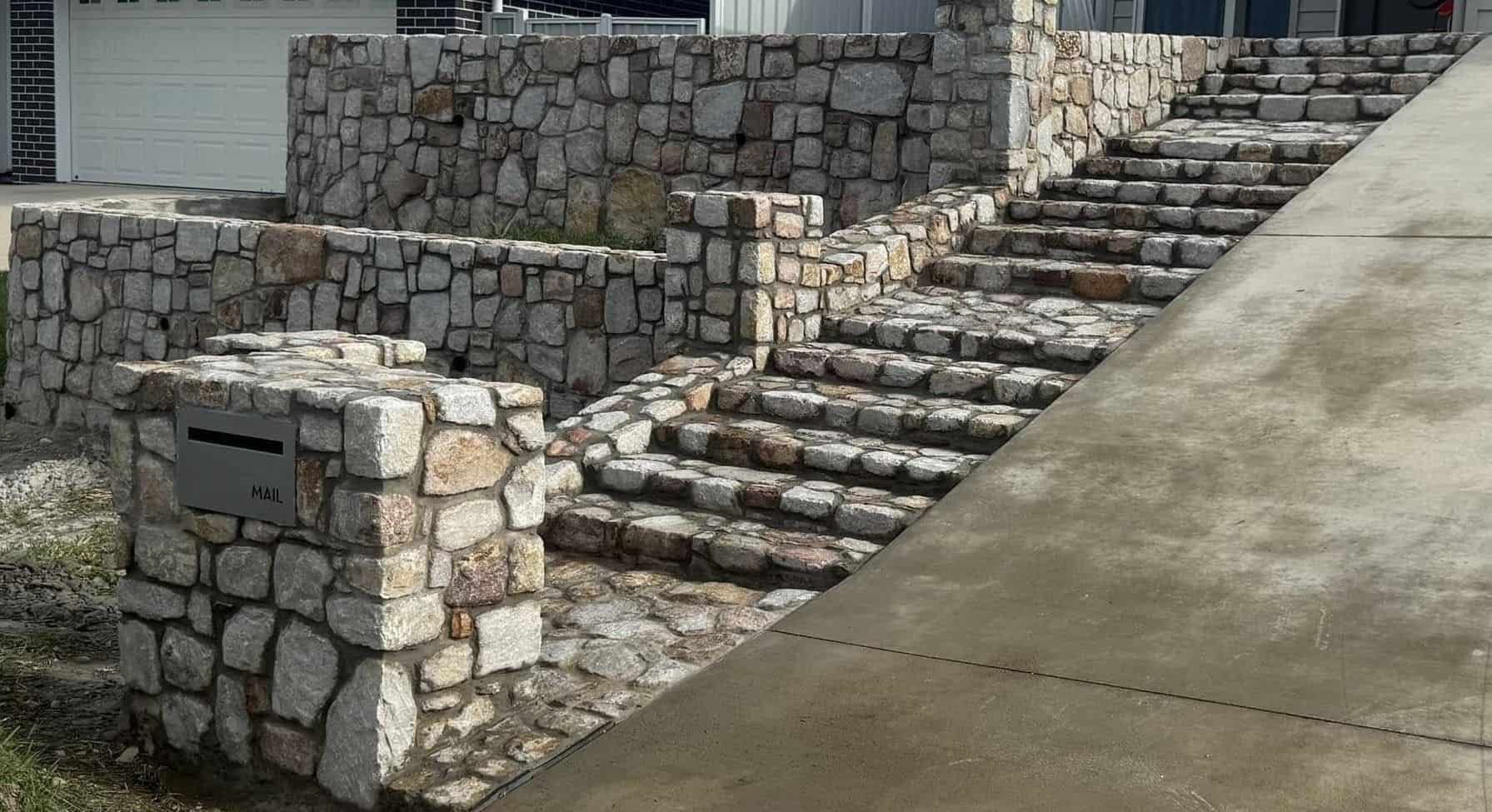 A Stone Wall With Stairs Leading Up to a House — Campbell's Truck and Bobcat and Landscape Supplies In Gympie, QLD