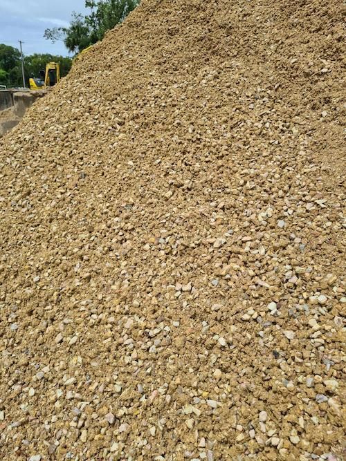 A Large Pile Of Gravel With A Yellow Excavator In The Background — Campbell's Truck and Bobcat and Landscape Supplies In Gympie, QLD