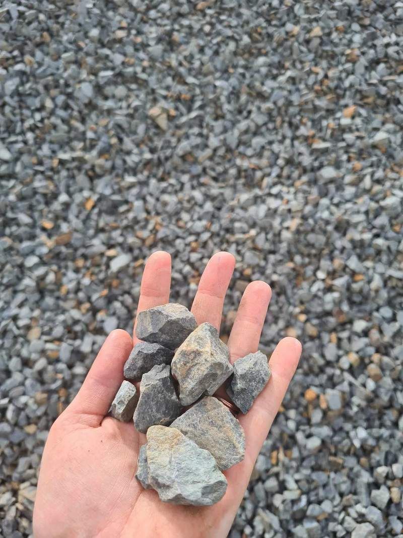 A Person Is Holding A Pile Of Rocks In Their Hand — Campbell's Truck and Bobcat and Landscape Supplies In Gympie, QLD