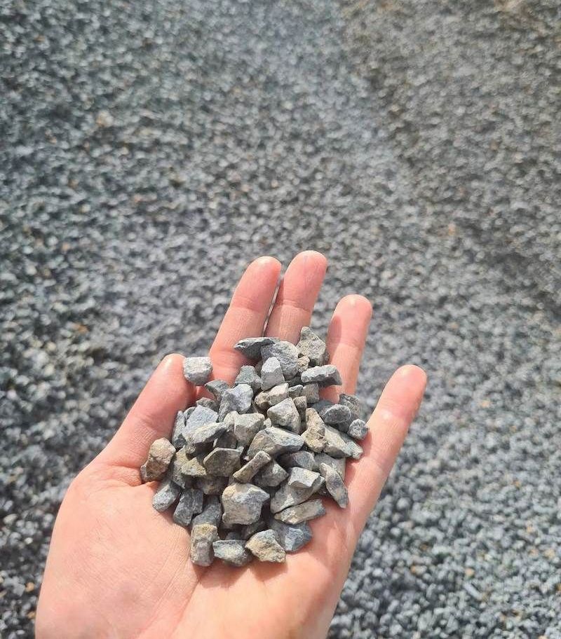 A Person Is Holding A Pile Of Gravel In Their Hand — Campbell's Truck and Bobcat and Landscape Supplies In Gympie, QLD