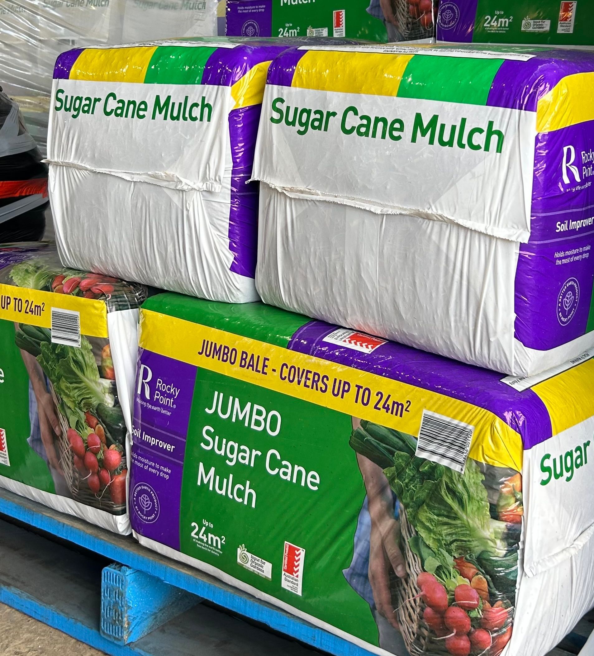 Boxes of sugar cane mulch are stacked on top of each other on a pallet.