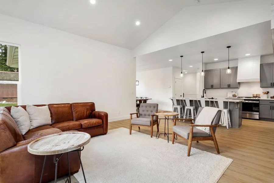 A living room with a brown couch , chairs , a table and a rug.