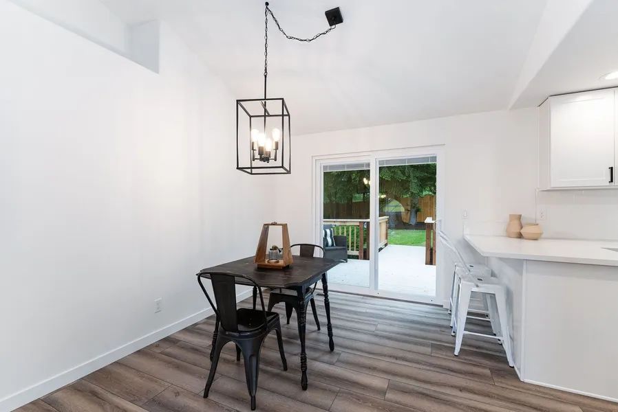 A dining room with a table and chairs and a chandelier hanging from the ceiling.