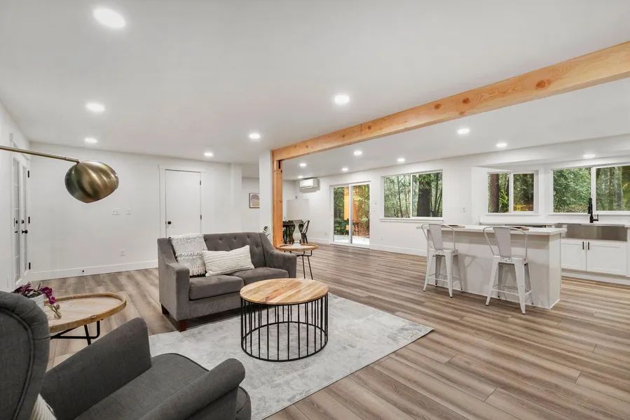A living room with a couch , chairs , tables and a kitchen.