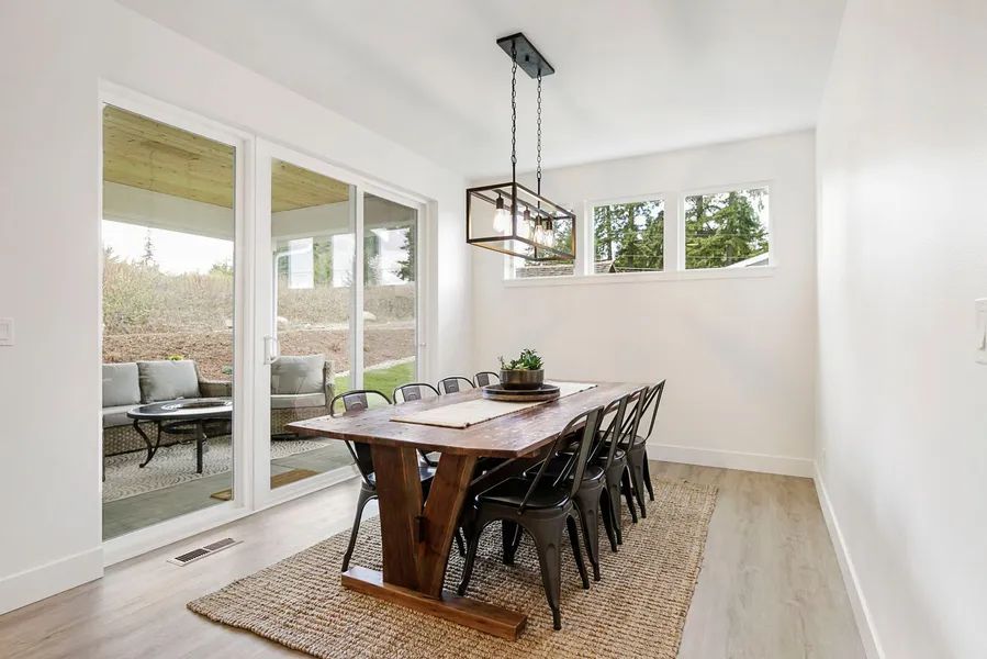 A dining room with a wooden table and chairs and sliding glass doors.