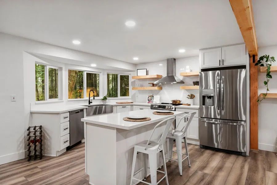 A kitchen with white cabinets , stainless steel appliances , and a large island.