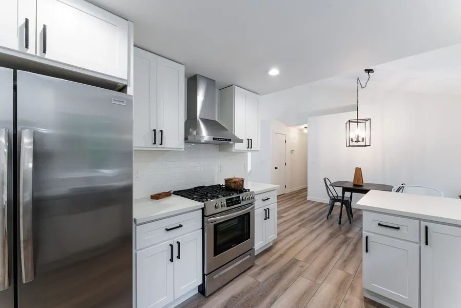 A kitchen with white cabinets , stainless steel appliances , a refrigerator and a stove.