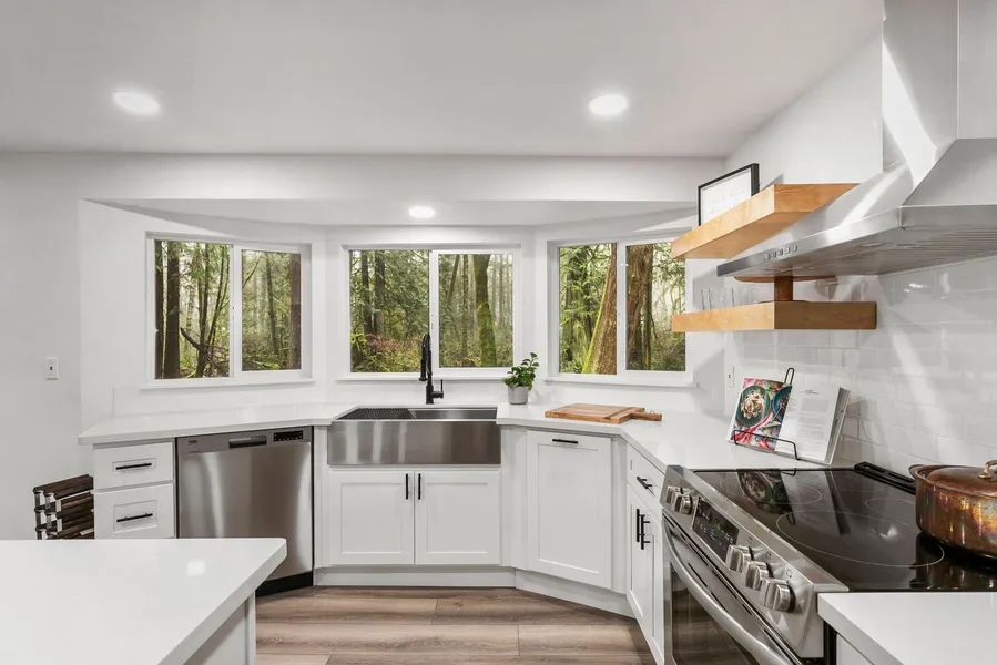 A kitchen with white cabinets , stainless steel appliances , a stove and a sink.