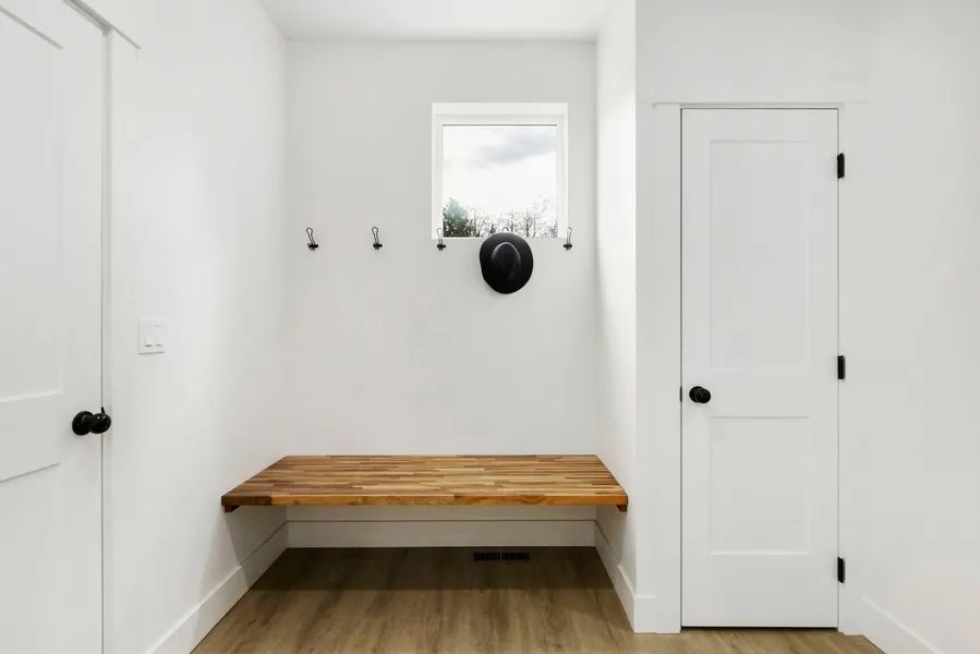 A white room with a wooden bench and a window.