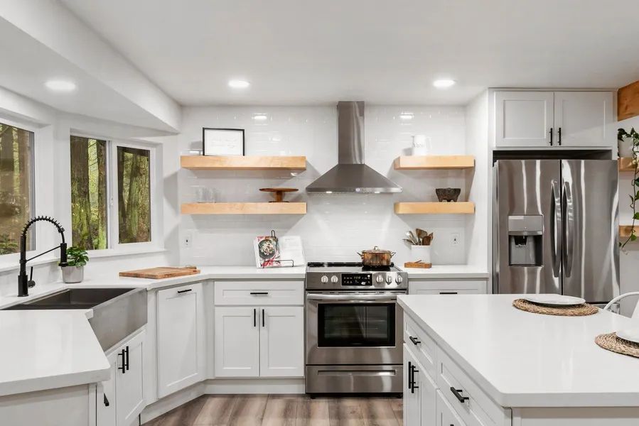 A kitchen with white cabinets , stainless steel appliances , a sink , and a refrigerator.