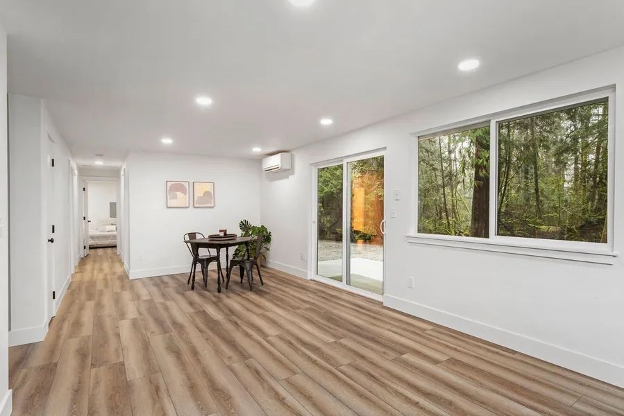 A living room with hardwood floors , a table and chairs , and a sliding glass door.