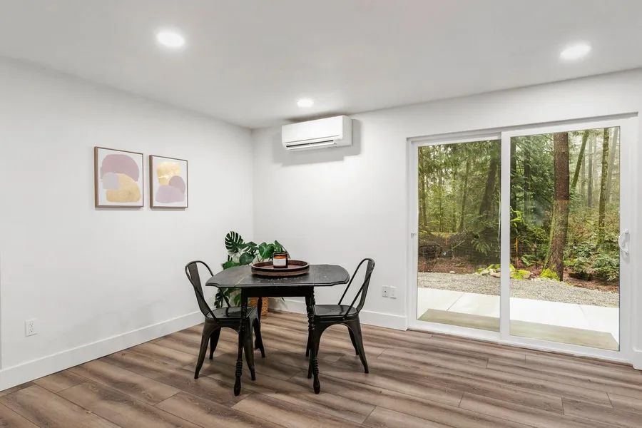 A dining room with a table and chairs and a sliding glass door.