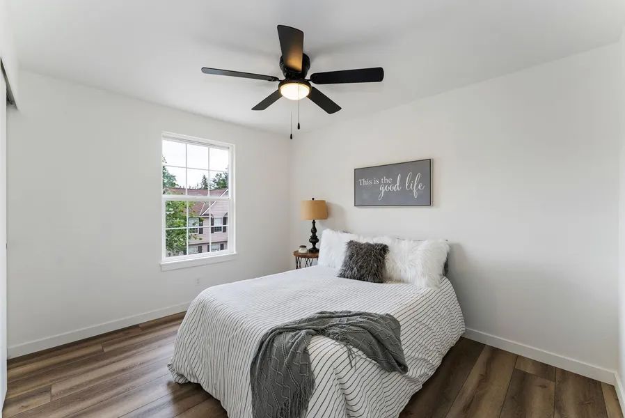 A bedroom with a bed , ceiling fan , and window.