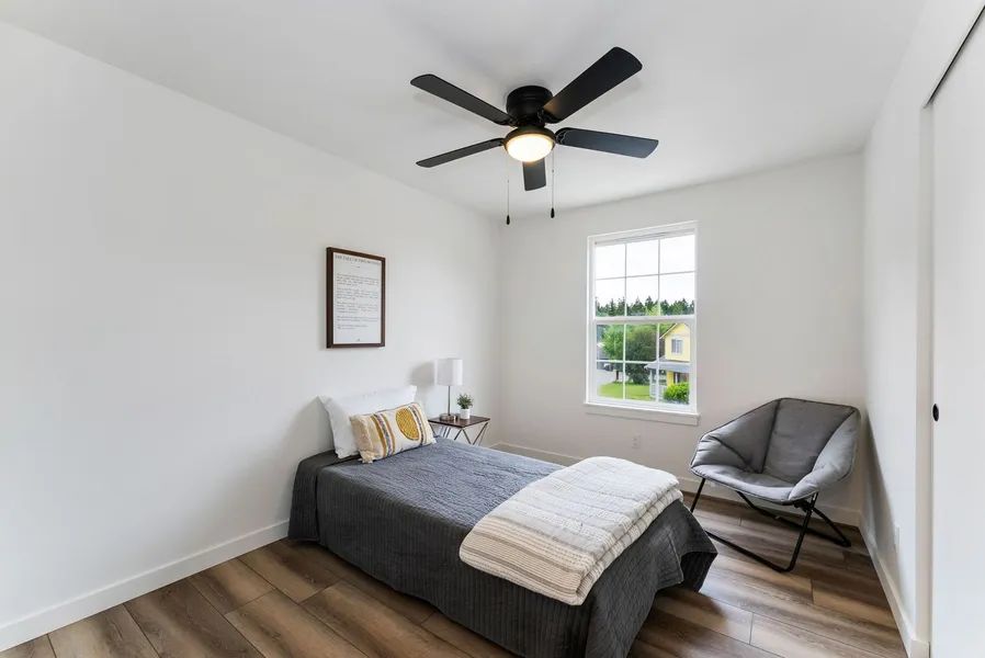 A bedroom with a single bed , chair and ceiling fan.