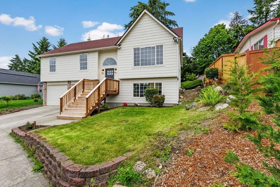 A white house with a wooden deck and stairs in front of it.