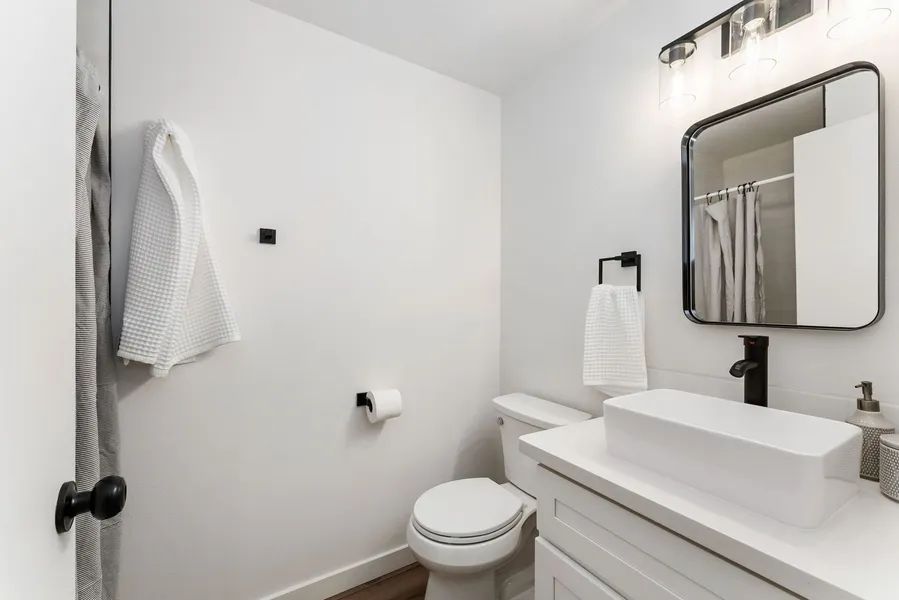 A bathroom with a toilet , sink , mirror and shower.