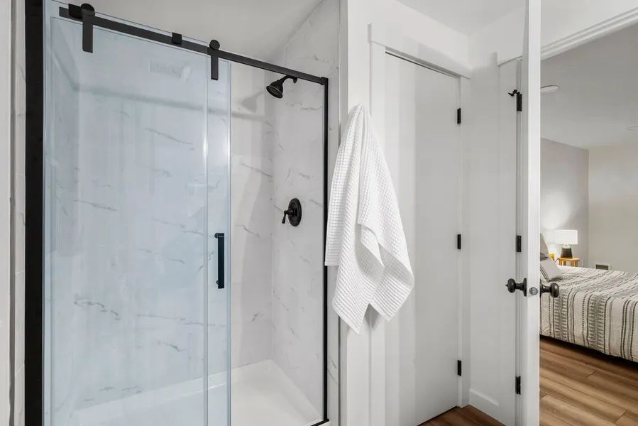 A bathroom with a sliding glass shower door and a towel hanging on the wall.