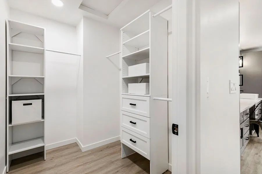 A walk in closet with lots of shelves and drawers in a house.