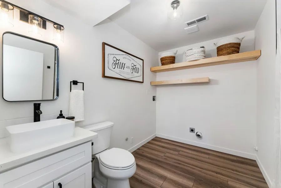 A bathroom with a toilet , sink and mirror.