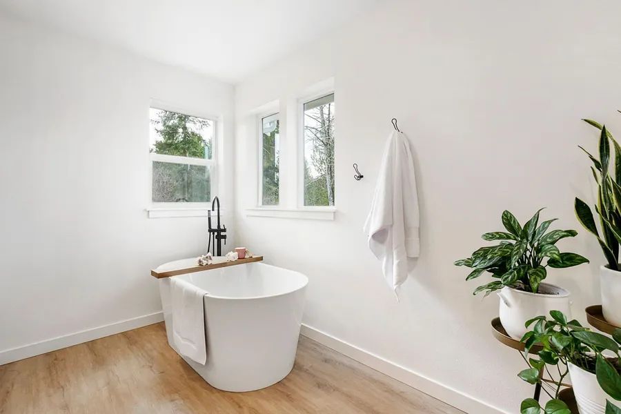 A bathroom with a bathtub and potted plants.