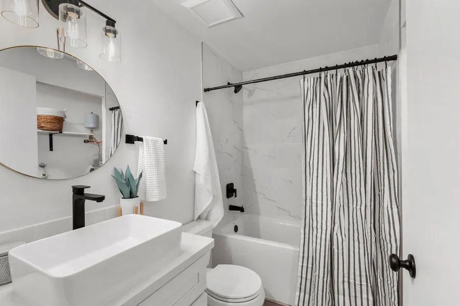 A bathroom with a sink , toilet , shower and mirror.