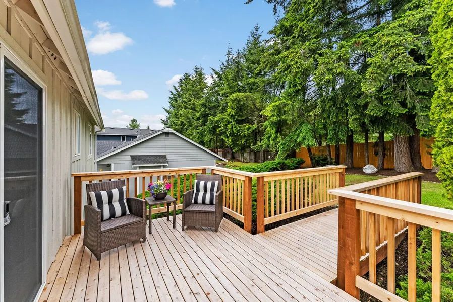 There is a wooden deck with chairs and a table on it.