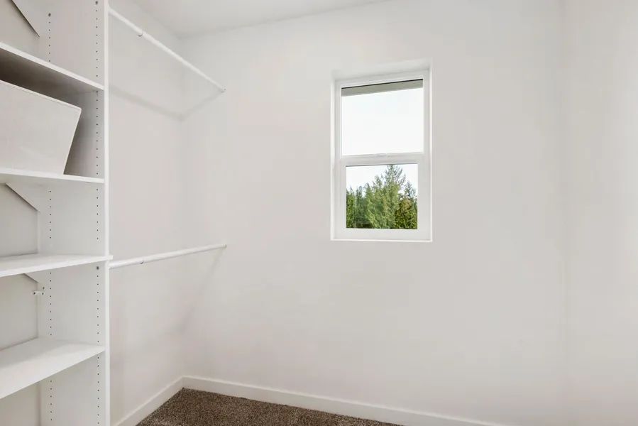 An empty walk in closet with shelves and a window.