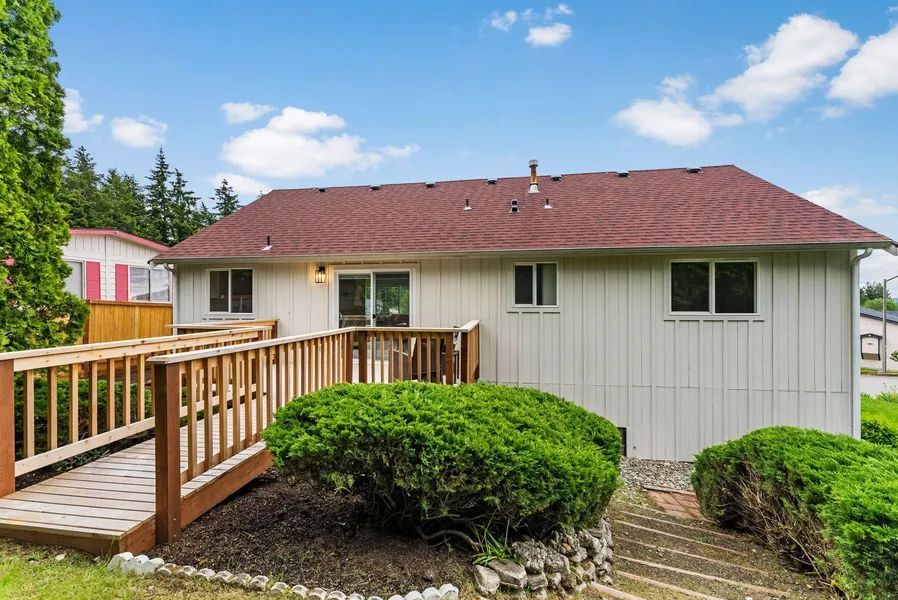 A white house with a red roof and a wooden walkway leading to it.