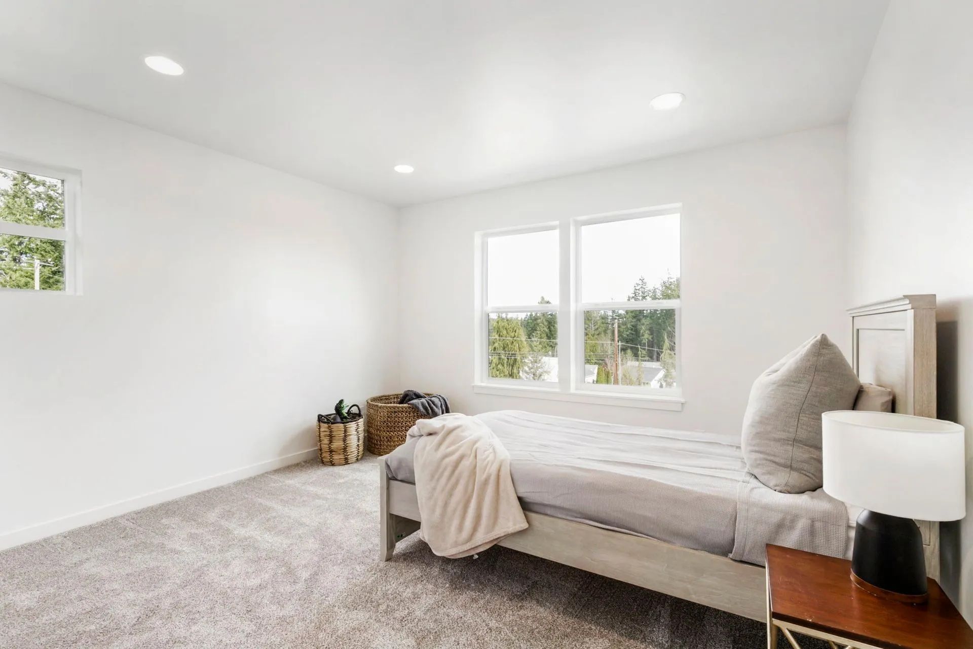 A bedroom with a bed , nightstand , and two windows.
