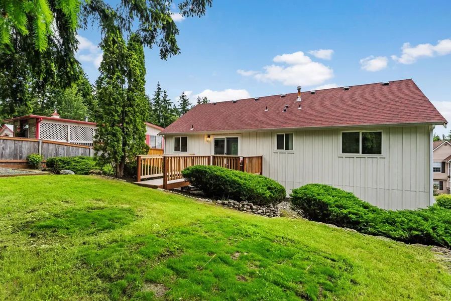 A white house with a red roof is sitting on top of a lush green hill.