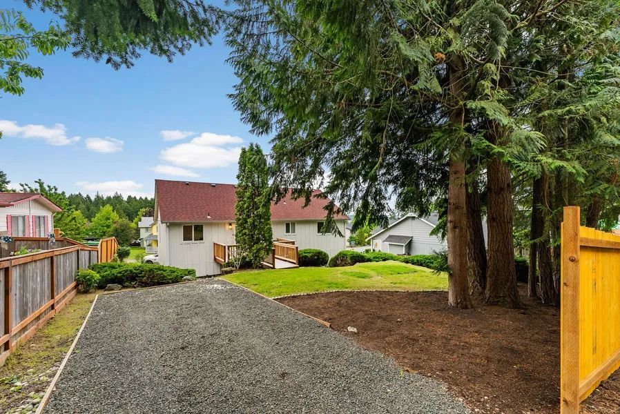 A gravel driveway leading to a house with a yellow fence.