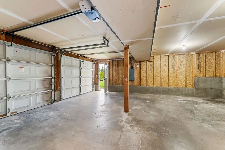An empty garage with two garage doors and a doorway.