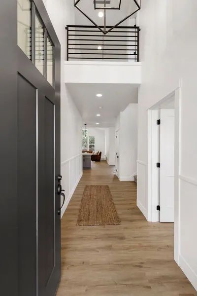 A hallway in a house with a black door and a rug on the floor.
