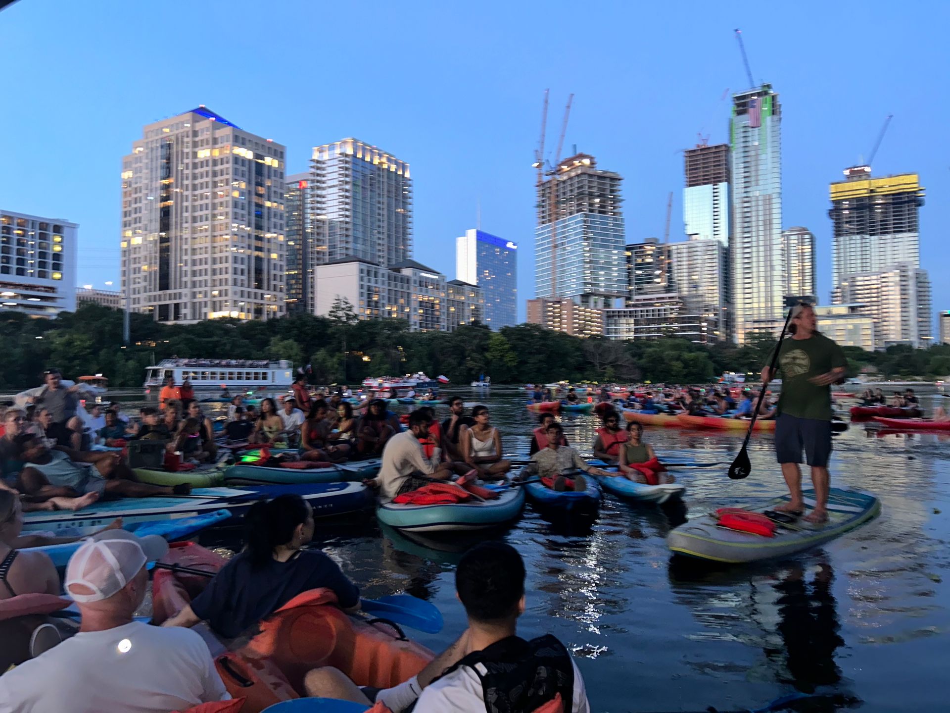 Kayakers on Lady Bird Lake paddling vigorously under the Congress Avenue Bridge.