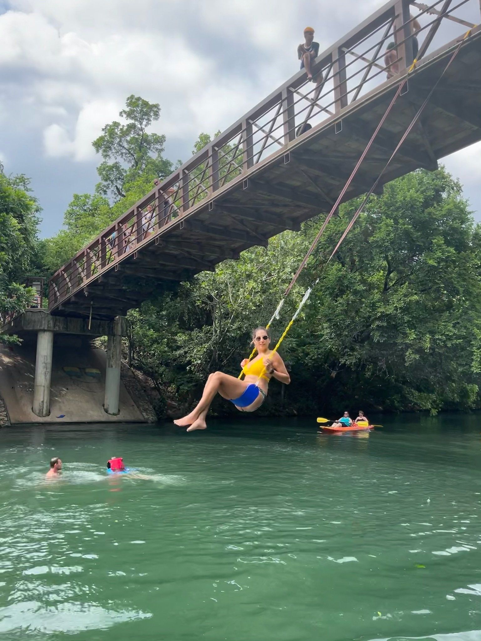 Girl on a swing at the barton springs pedestrian bridge
