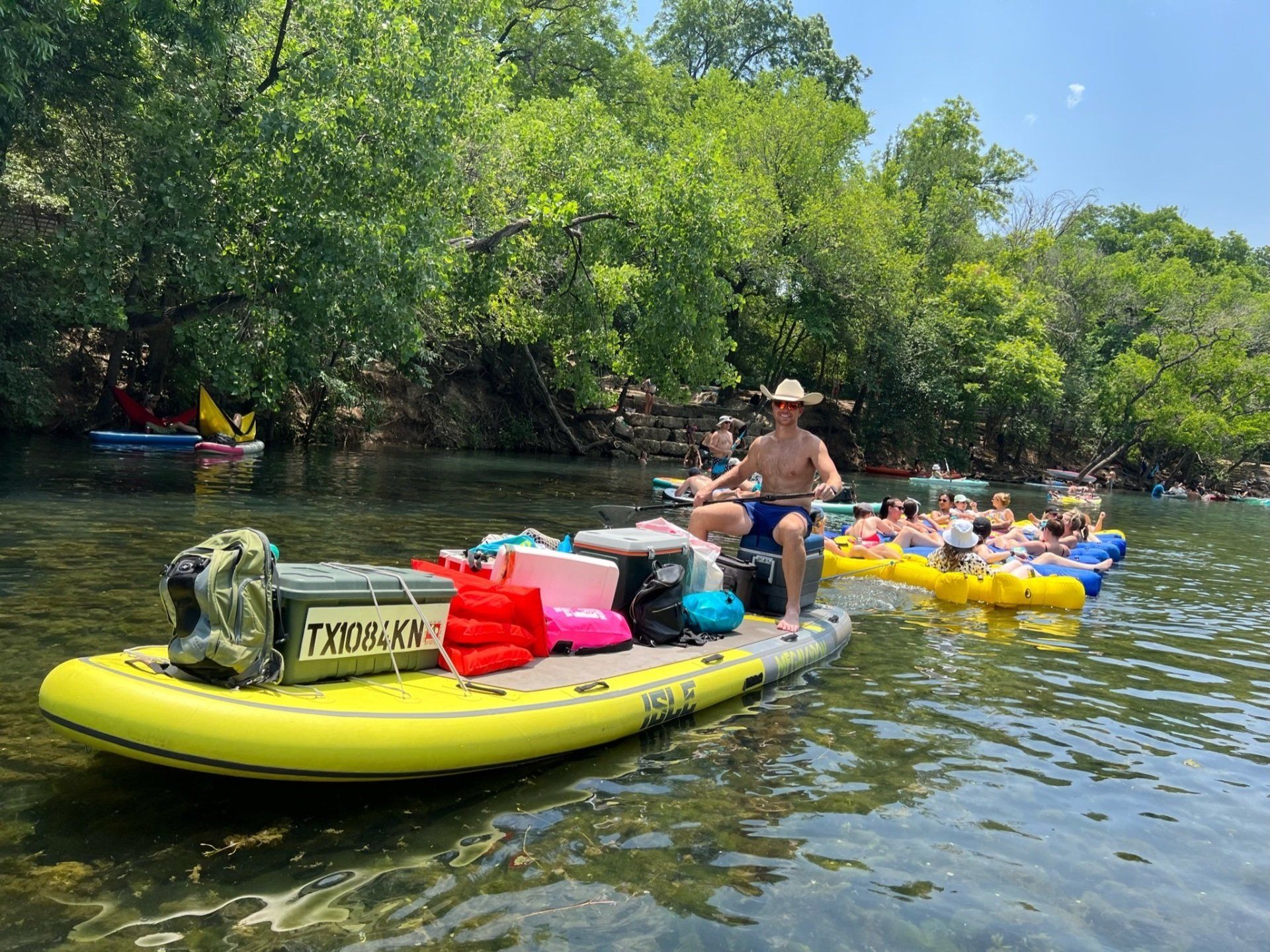 tour guide on giant paddle board pulling a tubing tour group in austin