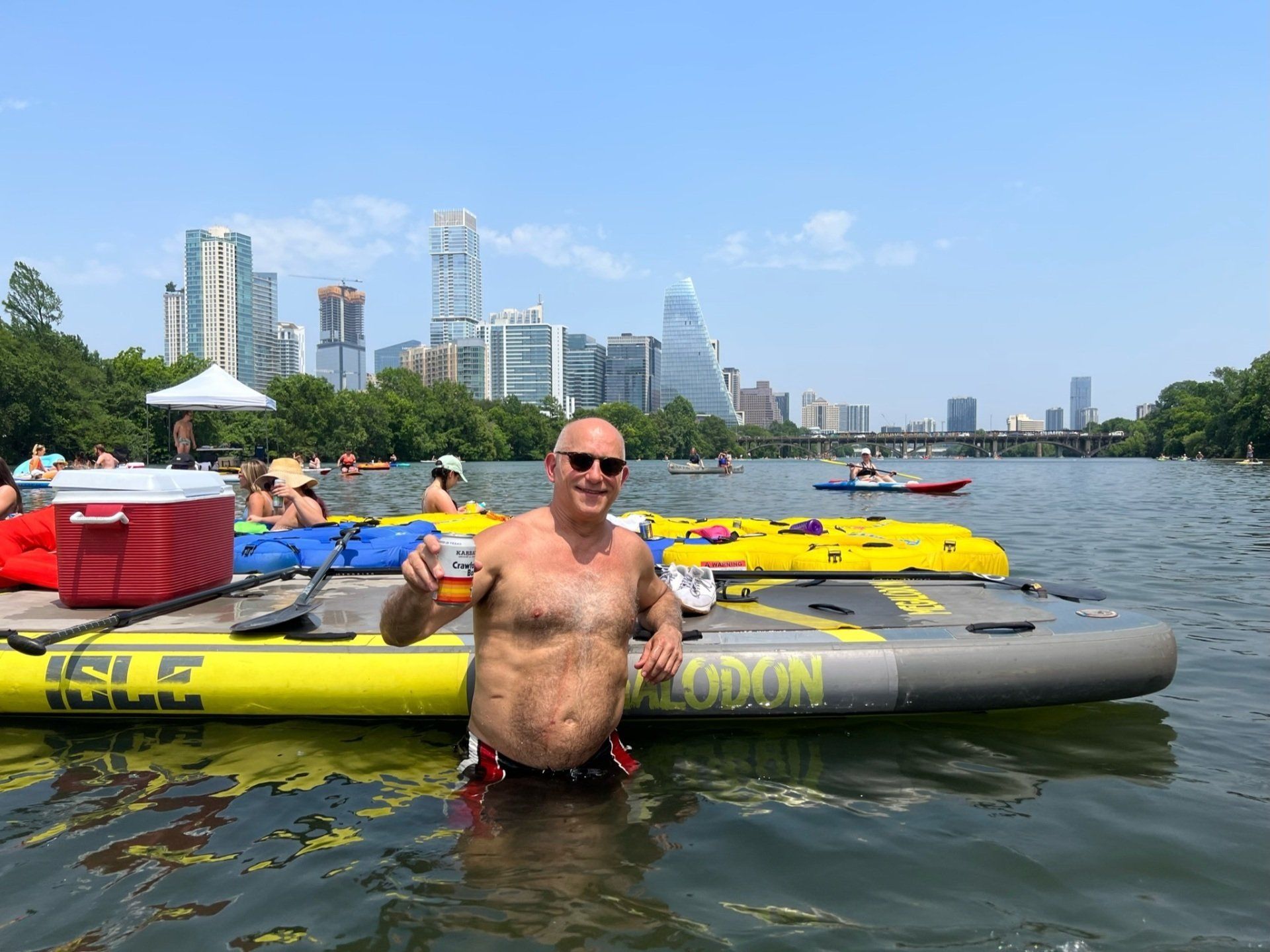 man holding up a beer in the water at party island in austin tx